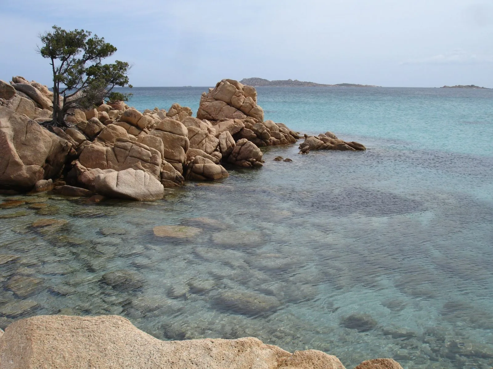Scogli di granito rosato e acqua trasparente a Capriccioli, con le isole all'orizzonte