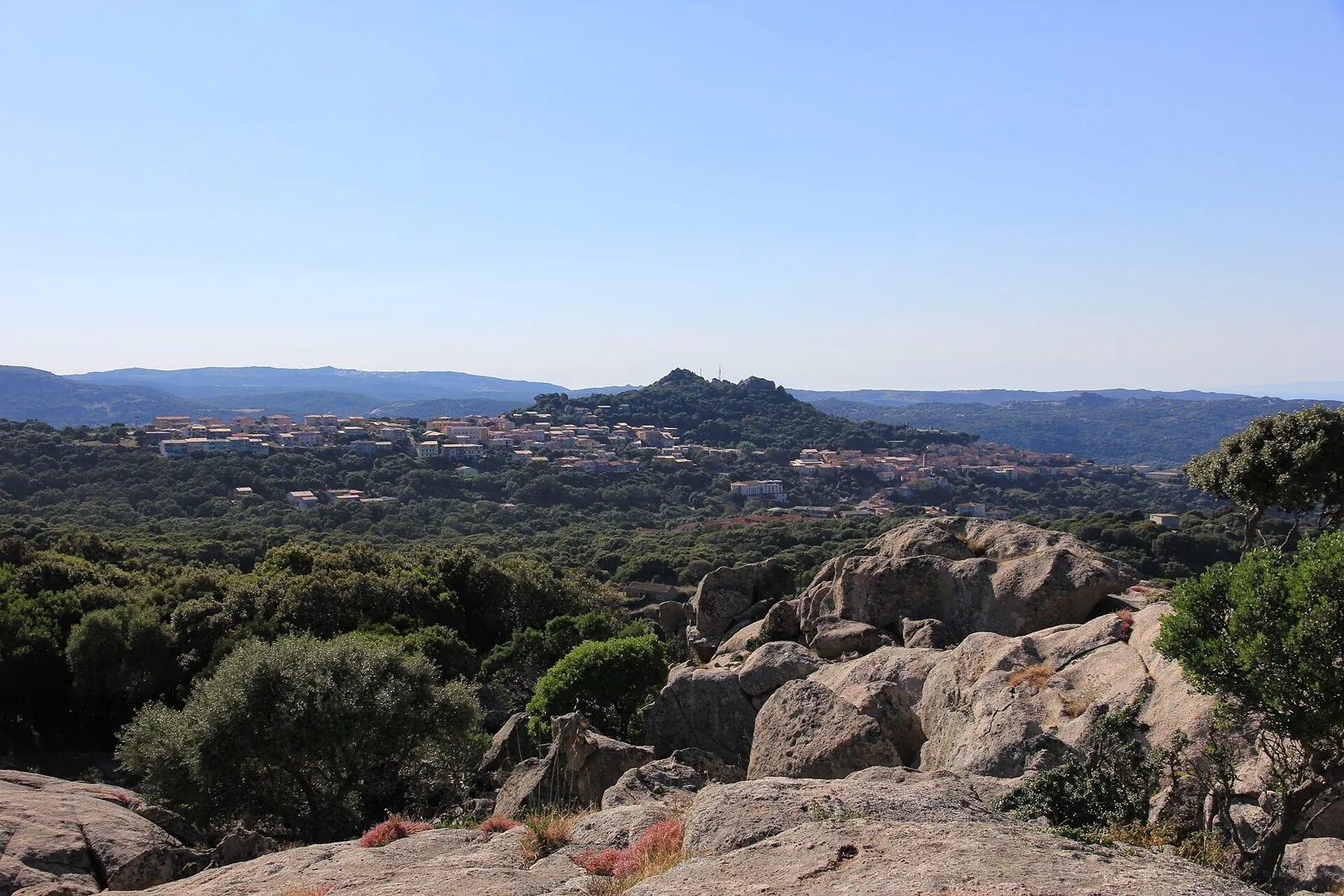 Rocce di granito e macchia mediterranea con il paese di Luogosanto sulla collina, nell'interno della Gallura
