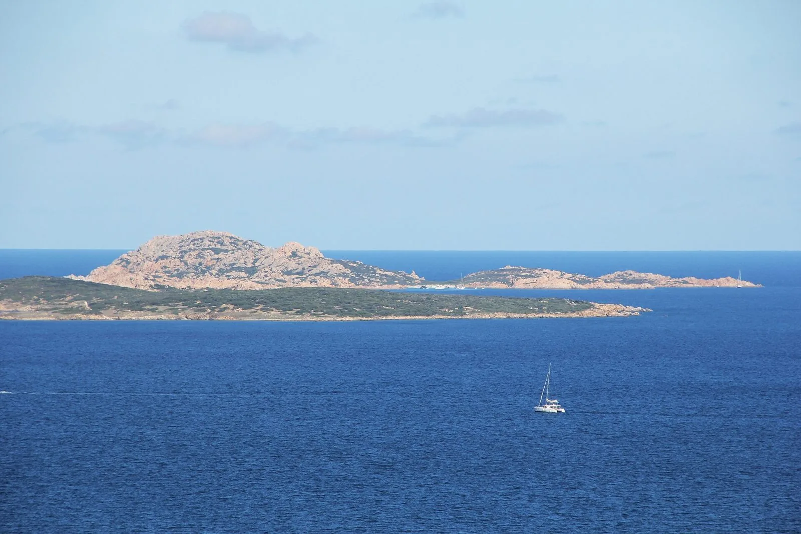 Mare blu intenso della Gallura con un catamarano a vela e l'isola di Mortorio sullo sfondo